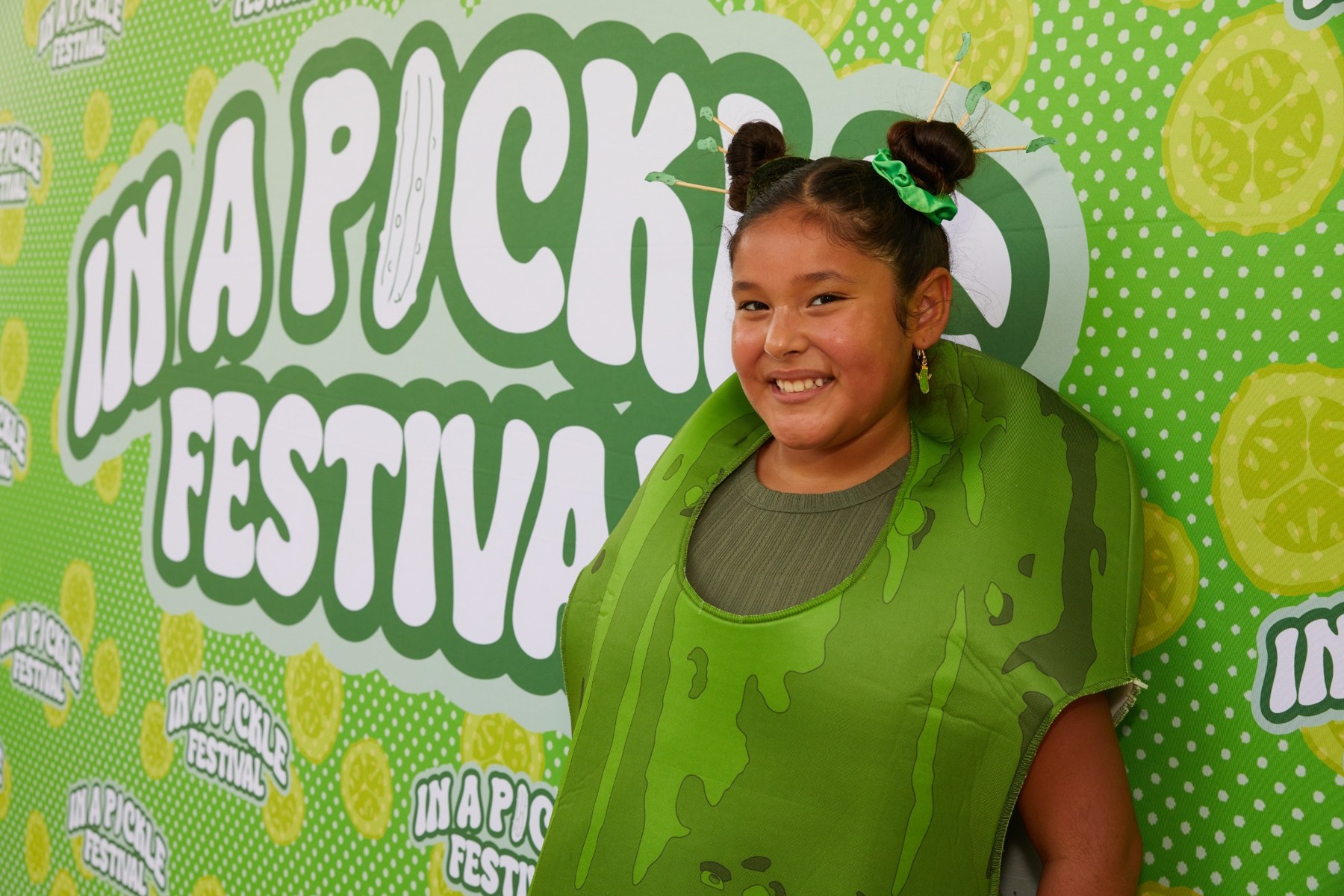 Festival guest posing at the pickle backdrop