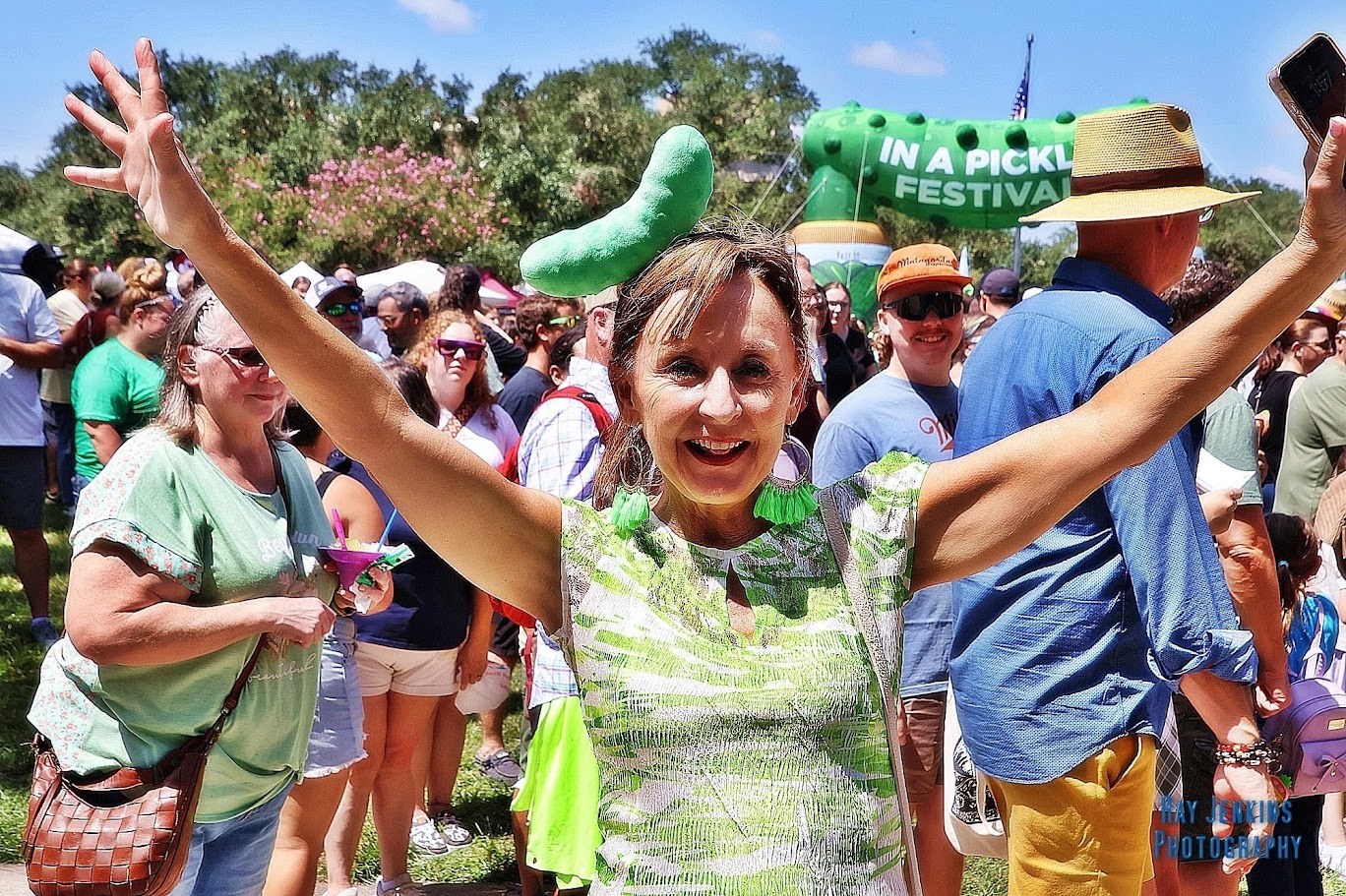 A smiling festival guest cheering with arms raised
